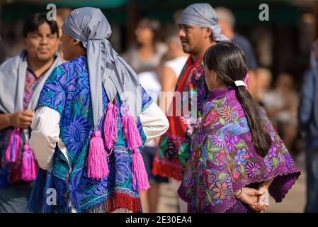 Gruppe von Mexikanern mit traditioneller Kleidung mit floraler Struktur und kariertem Kopfschmuck mit Fuchsia-Quasten, Dorf Zinacantan, Chiapas, Mexiko. Stockfoto
