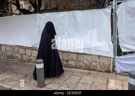 Ein Mitglied der sogenannten Haredi Burqa Sekte, auch bekannt als "Shawl Women" (jüdische religiöse Gruppe, in der ultra-orthodoxe jüdische Frauen behaupten, dass Bescheidenheit eine burka-artige Abdeckung des gesamten Körpers erfordert), geht durch Mea Shearim, ein ultra-orthodoxes Viertel in West-Jerusalem, Israel. Die Shalim, allgemein bekannt als der "Burka-Kult", ist eine der isoliertesten und verunglimpftesten Sekten in Israel, selbst unter der ultra-orthodoxen Bevölkerung des Landes. Stockfoto