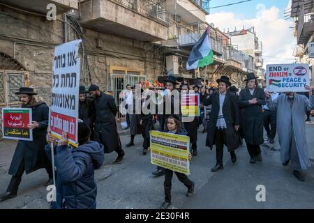 Mitglieder der Neturei Karta, einer Randbewegung ultra-orthodoxer jüdischer Bewegungen innerhalb des antizionistischen Blocks, tragen die palästinensische Flagge und rufen Slogans, während sie am 14. Januar 2021 in Jerusalem, Israel, durch das religiöse Viertel Mea Shearim gehen. Neturei Karta lehnt den Zionismus ab und fordert eine "friedliche Zerschlagung" des Staates Israel, in dem Glauben, dass Juden bis zum Kommen des jüdischen Messias verboten sind, ihren eigenen Staat zu haben und dass der Staat Israel eine Rebellion gegen Gott ist. Stockfoto