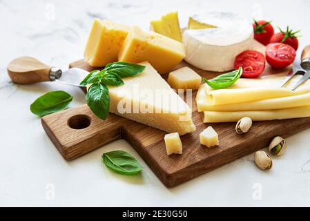 Verschiedene Käsesorten, Weintrauben und Snacks auf weißem Marmorboden Stockfoto