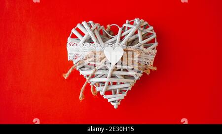 Weißes handgemachtes Herz auf rotem Hintergrund mit Kopierraum. Valentinstagskonzept. Stockfoto