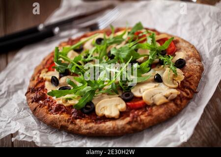 Pizza mit Käse, Tomaten, Champignon, Oliven und Arugola. Stockfoto