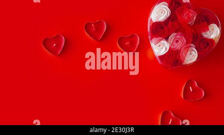 Valentinstag Geschenk auf einem roten Hintergrund. Viele rote und weiße Rosen in einem herzförmigen Paket, gebunden mit einem roten Band. Das Konzept der Liebe Stockfoto