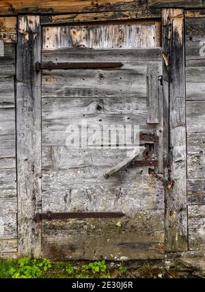 Alte geschlossene Holztür mit Schnitzereien in der Blockhütte. Stockfoto