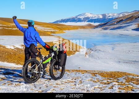 Männliche Reisende auf einem Fahrrad im Winter in den Bergen. Reisen im Winter. Hochplateau Turgen-ASY, Kasachstan Stockfoto