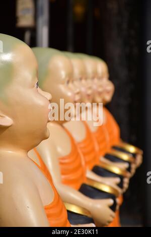 Ein Seitenprofil perspektivische Ansicht von Statuen von buddhistischen Mönchen tragen Safran Roben und halten Almosenschüsseln. Stockfoto