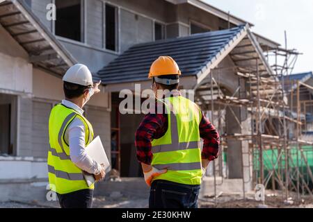 Der Ingenieur empfiehlt dem Vorgesetzten auf der Baustelle den Hausbau. Hausbaukonzept. Stockfoto