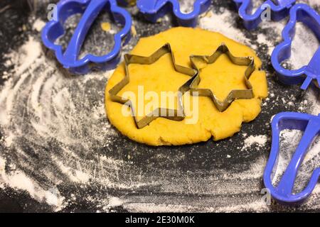 Sternförmige Ausstechformen und Teig, schwarze Tafel mit Mehl bestreut Stockfoto