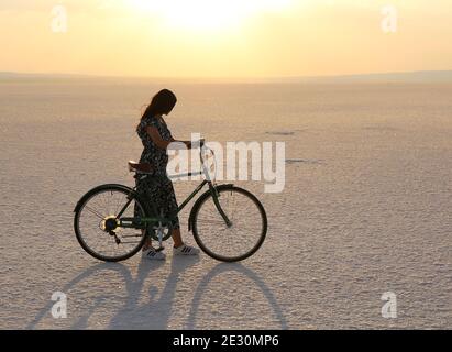 TUZ GOLU,AKSARAY,TÜRKEI-JULI 22:Unidentifiziertes Mädchen mit einem Fahrrad während Sonnenuntergang am Salt Lake.Juli 22,2017 in Tuz Golu,Aksaray,Türkei. Stockfoto