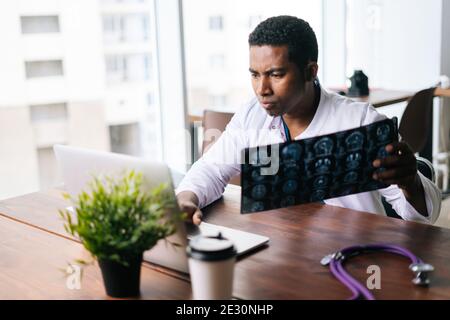 Afroamerikanischer schwarzer Mann Arzt Untersuchung MRI Gehirn Scan-Bild Während der Arbeit am Schreibtisch Stockfoto