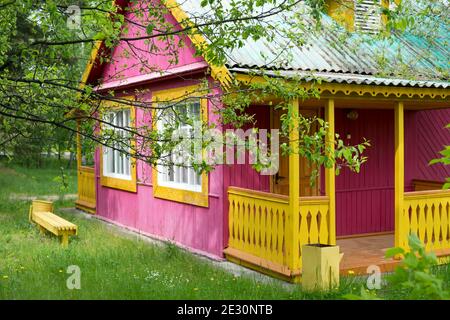 Ein kleines Gästehaus aus Holz versteckt im Garten hinter Apfelbäumen an einem Sommertag. Stockfoto