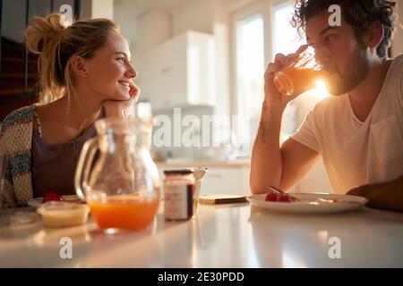 Ein junges Paar in der Liebe entspannen am Tisch nach dem Frühstück an einem schönen sonnigen Morgen zu Hause. Beziehung, Liebe, zusammen, Frühstück Stockfoto