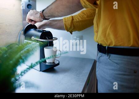 Ein junger Mann, der in entspannter Atmosphäre in der Küche einen Tee zubereitet. Routine, Morgen Stockfoto