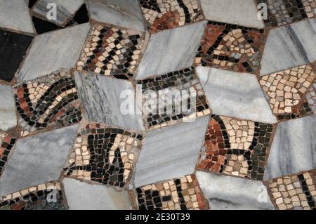 Die quadratischen Mosaiksteine des antiken Mosaiks sind in dieser Detailansicht von einem Teil des Pflasters in der byzantinischen Basilika San Vitale in Ravenna, Emilia Romagna, Italien, durch geäderte graue Marmoren unterteilt. Die Kirche wurde im Jahre 547 n. Chr. geweiht, aber obwohl einige der Bodenmosaiken ursprüngliche byzantinische Arbeit sind, vor allem an der Peripherie, sind andere neuere oder Rekonstruktionen. Stockfoto