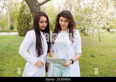 Ärztinnen Studenten im Freien. Medizinische Hintergrund. Studenten in der Nähe von Krankenhaus im Blumengarten. Stockfoto