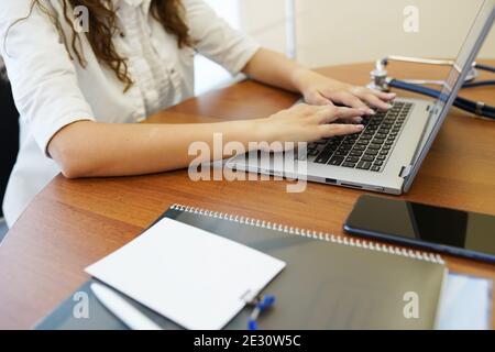 Nahaufnahme von einer Ärztin, die Eingabe auf Laptop-Computer, am Tisch im Krankenhaus Stockfoto