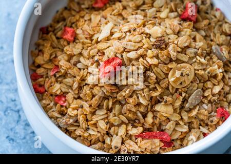 Im Ofen gebackenes Artisan-Müsli mit getrockneten Erdbeeren und Chia-Samen in Schüssel. Bereit zum Essen. Stockfoto