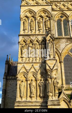 Nahaufnahme eines sonnendurchfluteten Abschnitts der Great West Front zur Salisbury Cathedral, Salisbury, Wiltshire, Großbritannien. Stockfoto