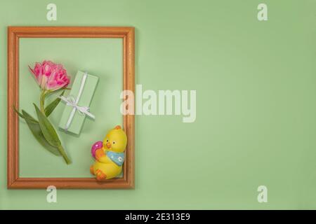 Gruß Frühlingskarte für Ostern, Muttertag. Schöne Frühlingskomposition. Holzrahmen einer lebhaften Frottee Tulpe, verpackt in grünem Papier, ein Geschenk und ein Stockfoto