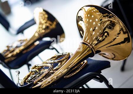 Zwei alte goldene horn. Auf einem blauen Stuhl liegen goldene Blasinstrumente aus Messing. Während der Pause des Musikkonzerts legten die Musiker das h Stockfoto