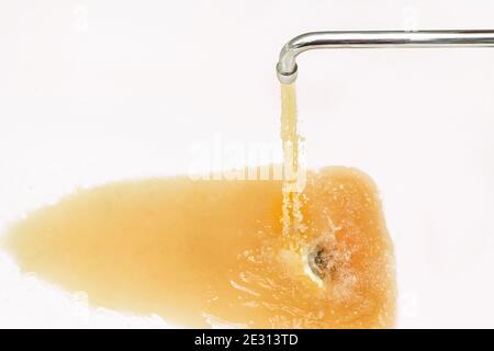 Rostiges oder schmutziges Wasser, das aus einem Wasserhahn in eine weiße Badewanne oder ein Waschbecken fließt. Stockfoto