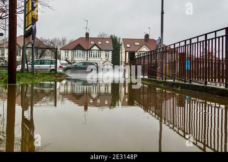 Das Auto spritzt durch die Pfütze, die sich während der lokalen Überschwemmungen auf der A41 in Nord-London nach starken Regenfällen gebildet hat. Stockfoto