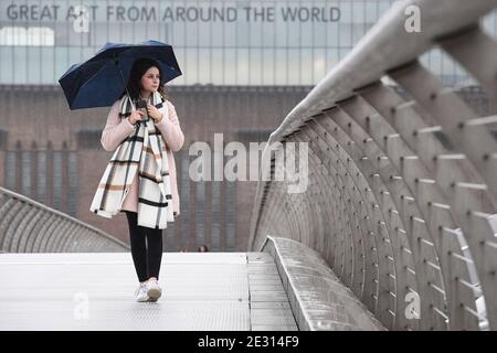 Eine Person geht im Regen über die Millennium Bridge in London. Teile von Ostengland könnten am Samstag bis zu 10 cm Schnee sehen, als die Prognostiker vor dem Potenzial für "signifikante Störungen" warnten. Stockfoto