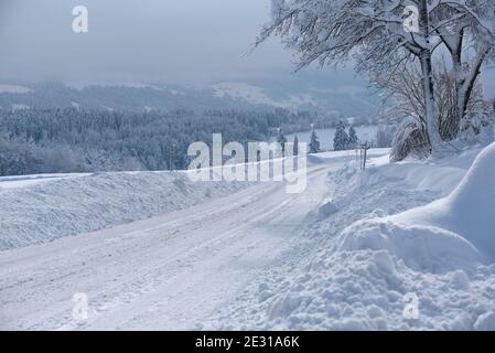 Scheidegg, Bayern, Deutschland, 15. Januar 2021: Schneesturm in Bayern. Blick auf die gereinigte Straße nach einem Schneekklon Stockfoto