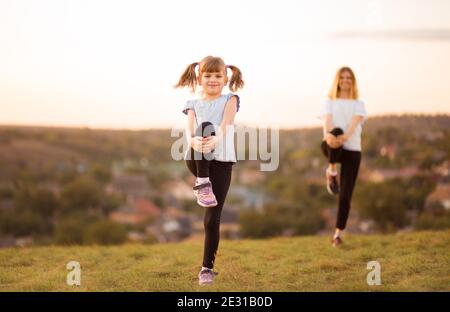 Sportliche Mutter und Tochter. Frauen- und Kindertraining im Park. Outdoor-Sport. Gesunder Sport. Fitness, Yoga. Stockfoto