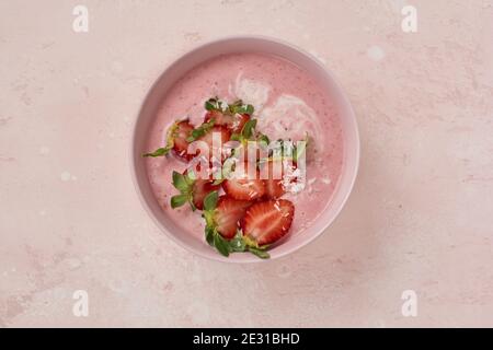 Frühstück mit Müsli, Kokosnuss und Erdbeer Smoothie in einer Schüssel auf einem rosa hellen Hintergrund. Stockfoto