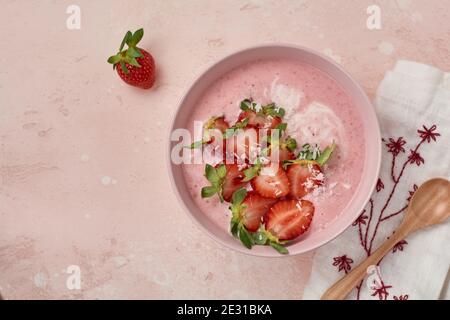 Frühstück mit Müsli, Kokosnuss und Erdbeer Smoothie in einer Schüssel auf einem rosa hellen Hintergrund. Stockfoto