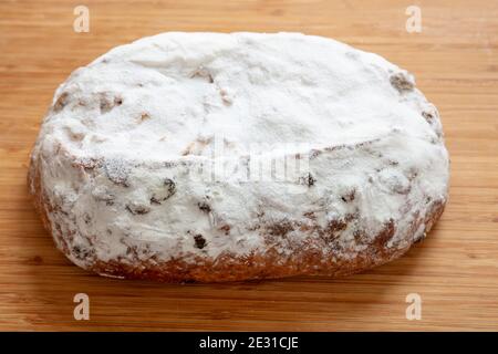 Christstollen Weihnachtsstollenkuchen isoliert auf Holztisch. Süßes, traditionelles deutsches Brot mit Rosinen, Nüssen, Gewürzen, Trockenfrüchten und Puderzucker Stockfoto