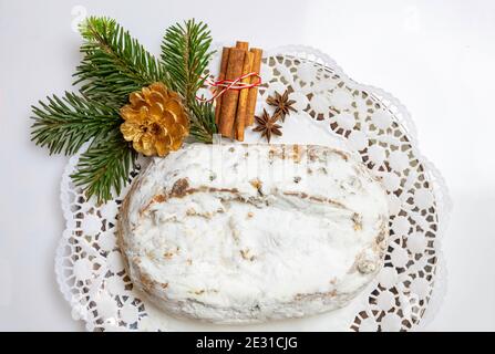 Christstollen Weihnachtsstollenkuchen und Dekoration auf weiß. Süßes traditionelles Brot mit Rosinen, Nüssen, Gewürzen, Trockenfrüchten und Puderzucker, Stockfoto