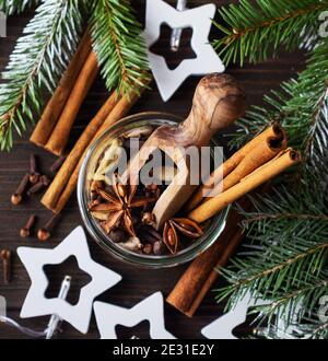 Mischung aus Glühweingewürzen in einem Glas Anis, Kardamom, Piment, Zimtstangen, Nelken auf dunklem Holzgrund. Für Text platzieren. Stockfoto