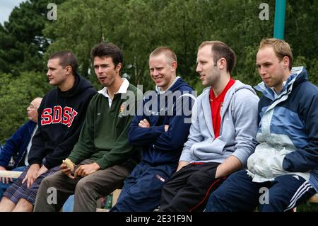 Eine Gruppe junger Männer, die auf einer Bank sitzen und etwas beobachten, wahrscheinlich ein Sportereignis, Großbritannien Stockfoto