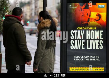London, Großbritannien. Januar 2021. Die Menschen stehen am Plakat einer öffentlichen Kampagne der Regierung "Haus retten, Leben retten" Covid-19 in London, da sich die Zahl der Fälle der mutierten Variante des SARS-Cov-2-Virus weiterhin im ganzen Land verbreitet. Kredit: SOPA Images Limited/Alamy Live Nachrichten Stockfoto