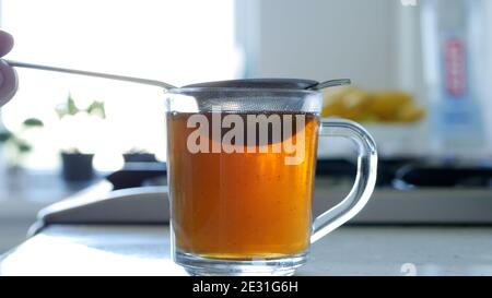 Bild mit der Herstellung eines heißen und aromatischen Tee mit einem Sieb und natürliche Tee Leafs Stockfoto