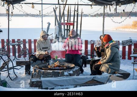 Gäste genießen heiße Getränke am Kamin im Café Regatta, einem kleinen, schrulligen Café im Freien am gefrorenen Meer in Helsinki, Finnland Stockfoto