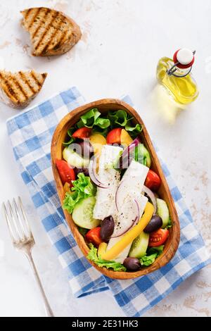 Griechischer Salat in Holzplatte auf weißem Hintergrund. Traditionelles griechisches Gericht. Selektiver Fokus. Draufsicht. Stockfoto