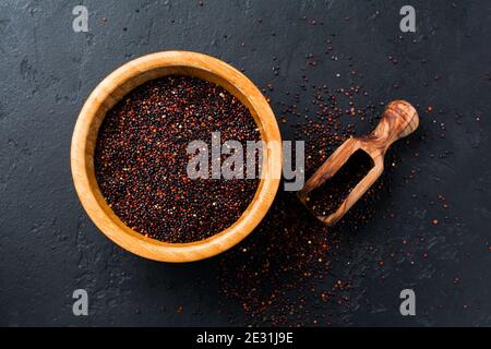 Schwarze Quinoa Körner Samen in einer Bambusschüssel auf schwarzem Stein Hintergrund. Flach liegend mit Kopierplatz. Stockfoto