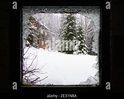 Draußen ist es kalt - Winterlandschaft durch ein kaputtes Fenster Stockfoto