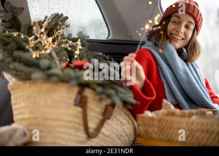 Frau lächelnd und Blick auf Sparkler, während im Auto sitzen Kofferraum Stockfoto