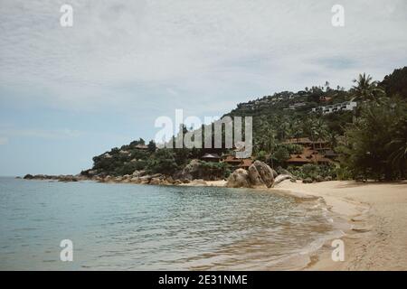 Tropischer Strand mit kleinen Strandhäusern und Resorts inmitten von Palmen Bäume auf dem Hügel Stockfoto