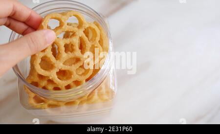 Eine Hand, die einen Wabenkekse herausnimmt, genannt Kuih loyang in Malaysia. Es ist ein beliebter frittierter Snack während Festivals. Stockfoto