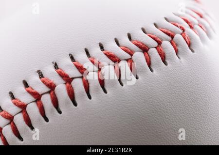 Nahaufnahme einer roten Fadennaht auf einem weißen Leder Baseball - Makroaufnahme Stockfoto