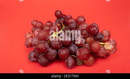 Frische rote Trauben auf rosa Hintergrund isoliert. Selektiver Fokus auf die frischen roten Trauben. Stockfoto