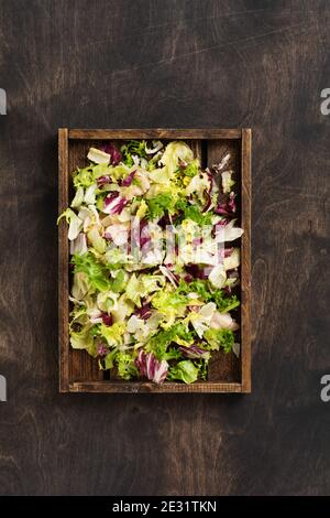 Mischen Sie frische Blätter von Rucola, Salat, Spinat, Rüben für Salat in Holzkiste auf Holz rustikalen Hintergrund. Selektiver Fokus. Stockfoto