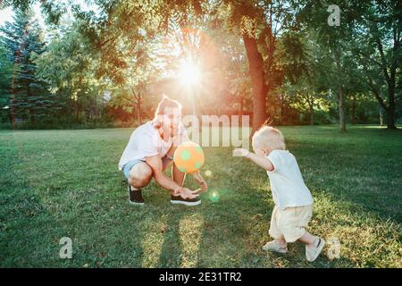 Vatertag. Vater spielt Ball mit Kleinkind Baby Junge im Freien. Elternteil verbringt Zeit zusammen mit Kind Sohn im Park. Authentische Lifestyle-Momente Stockfoto