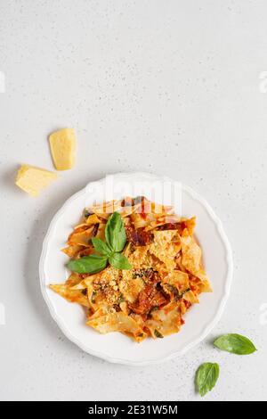 Pasta Maltagliati mit klassischer Tomatensauce, Parmesan und Basilikum auf einem rustikalen Beton hellen Tisch Hintergrund. Traditionelle italienische Gerichte. Top Vie Stockfoto