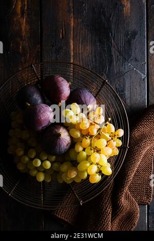 Frische Trauben und Feigen auf einem alten Holzhintergrund im Retro-Stil. Draufsicht. Stockfoto